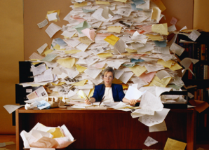 Businesswoman sitting at a desk with a large pile of paper by microsoft