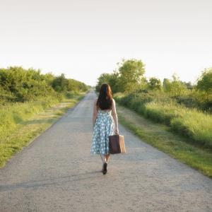 Femme avec valise sur la route